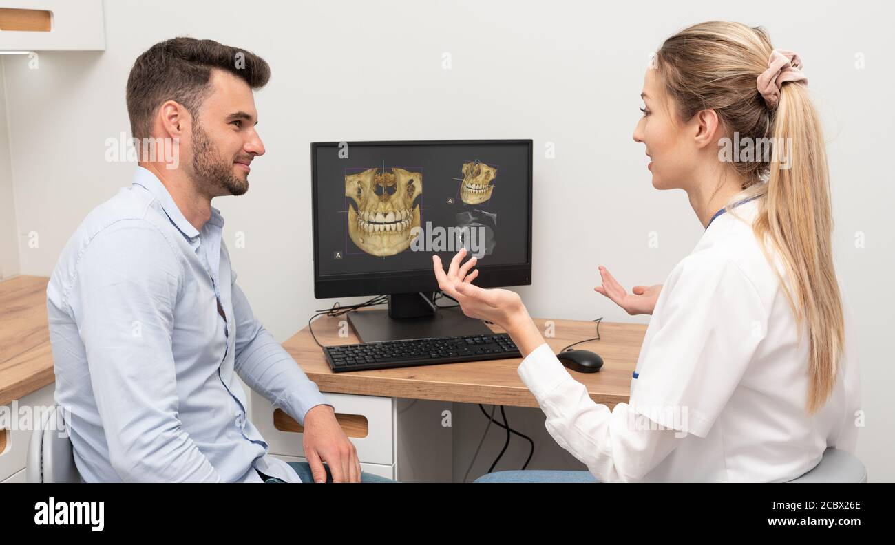 Diagnostic informatique de la tomographie dentaire. Le dentiste montre au patient une image radiologique à l'écran. Concept de soins dentaires. Banque D'Images