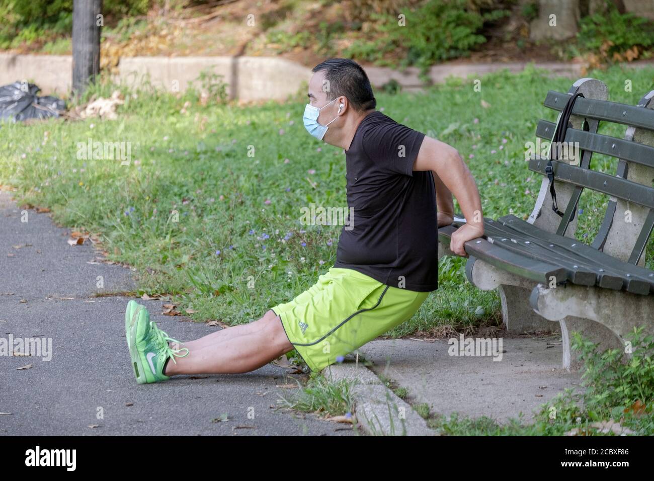 Un homme américain asiatique portant un masque chirurgical fait des exercices de plongée de banc dans un parc à Flushing, Queens, New York City. Banque D'Images