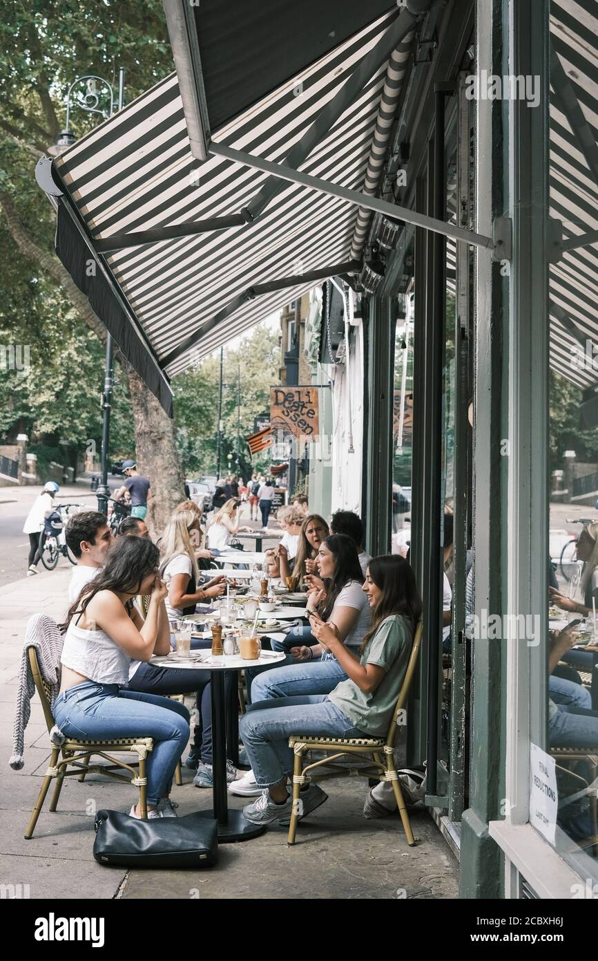 Un groupe de jeunes très beaux qui s'amusent à manger et à boire à l'extérieur d'un café à Hampstead, Londres, en été. Banque D'Images