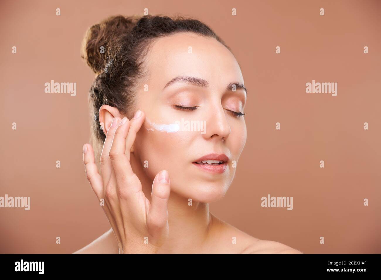 Jeune femme magnifique appliquant de la crème pour le visage ou du sérum sur le sous-œil zone Banque D'Images