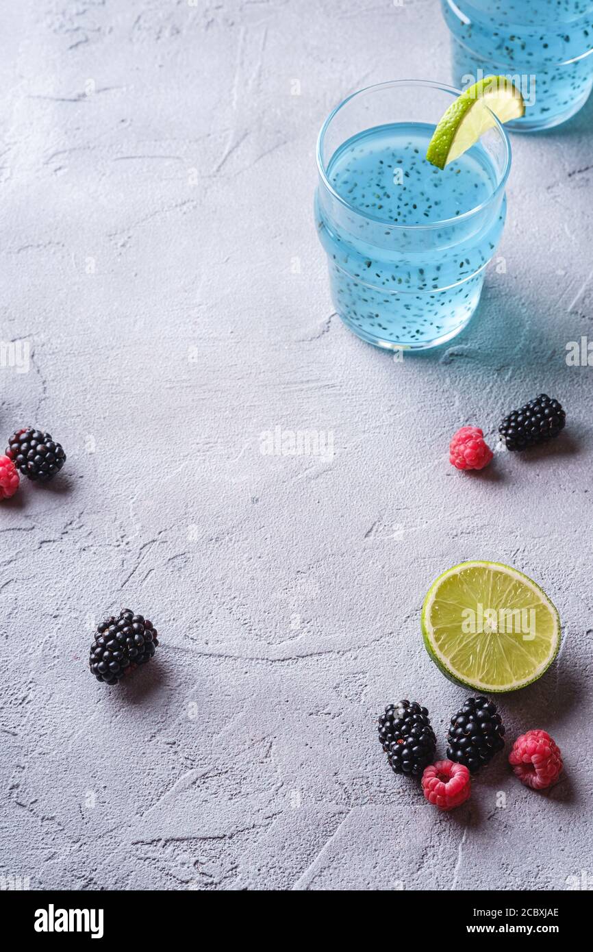 Délicieux cocktail de couleur bleue avec graines de basilic chia, tranche de citron vert, framboise et mûres dans deux verres, boisson d'été saine Banque D'Images