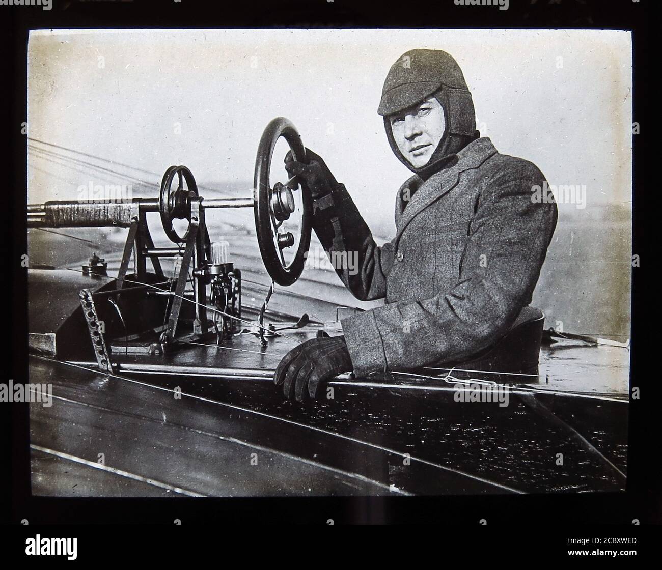 Une diapositive magique représentant l'aviateur du pionnier américain, John Moisant dans son monoplan ‘Moisant’. Il a été le premier à effectuer des vols de passagers au-dessus d'une ville (Paris), ainsi qu'à travers la Manche, de Paris à Londres. Seulement quelques mois après avoir été un pilote qualifié, Moisant est décédé après avoir été éjecté de son avion sur un champ à l'ouest de la Nouvelle-Orléans, en Louisiane, où il était en compétition pour la coupe Michelin 1910. Diapositive publiée par W. Butcher & Sons, Londres et datant d'environ 1914. Banque D'Images