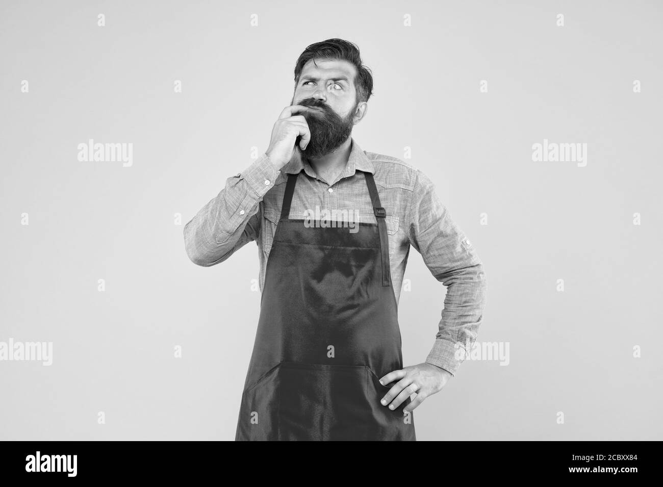 Prenez des décisions saines lors de la commande de nourriture au restaurant. Planifiez des repas hebdomadaires. Contrôle de cuisson chaque repas que vous faites. Hipster dans le tablier en pensant aux recettes. Recettes faciles à cuisiner. Recettes saines uniques. Banque D'Images