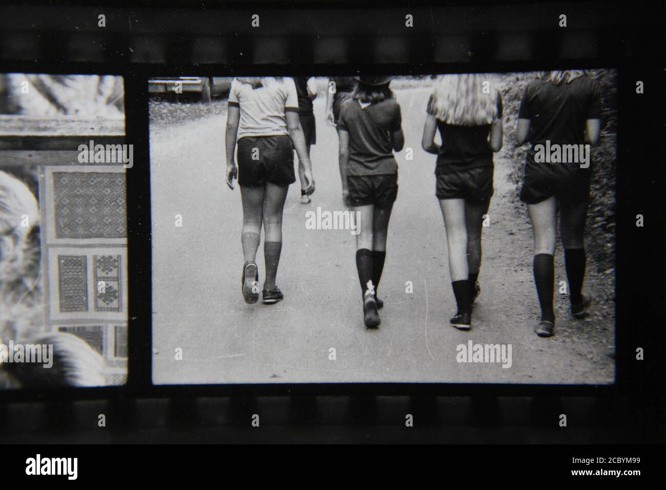 Belle photographie en noir et blanc vintage des années 1970 de quatre jeunes femmes qui marchent loin de l'appareil photo. Banque D'Images