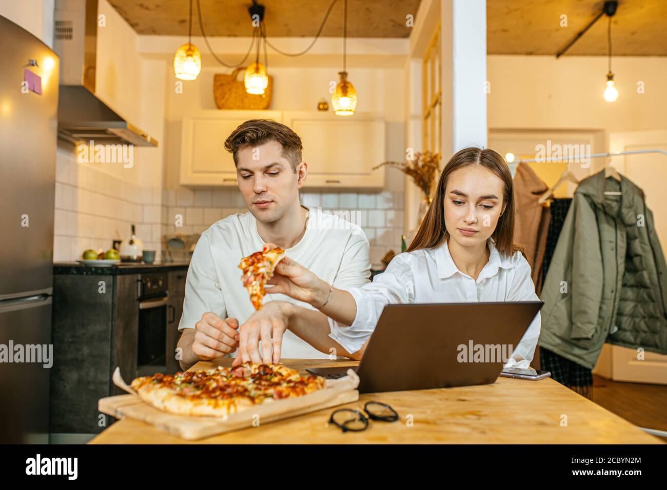 temps libre, temps libre de couples mariés caucasiens à la maison, homme et femme aiment manger la pizza reçue par le service de livraison, ils regardent le film dans ordinateur portable Banque D'Images