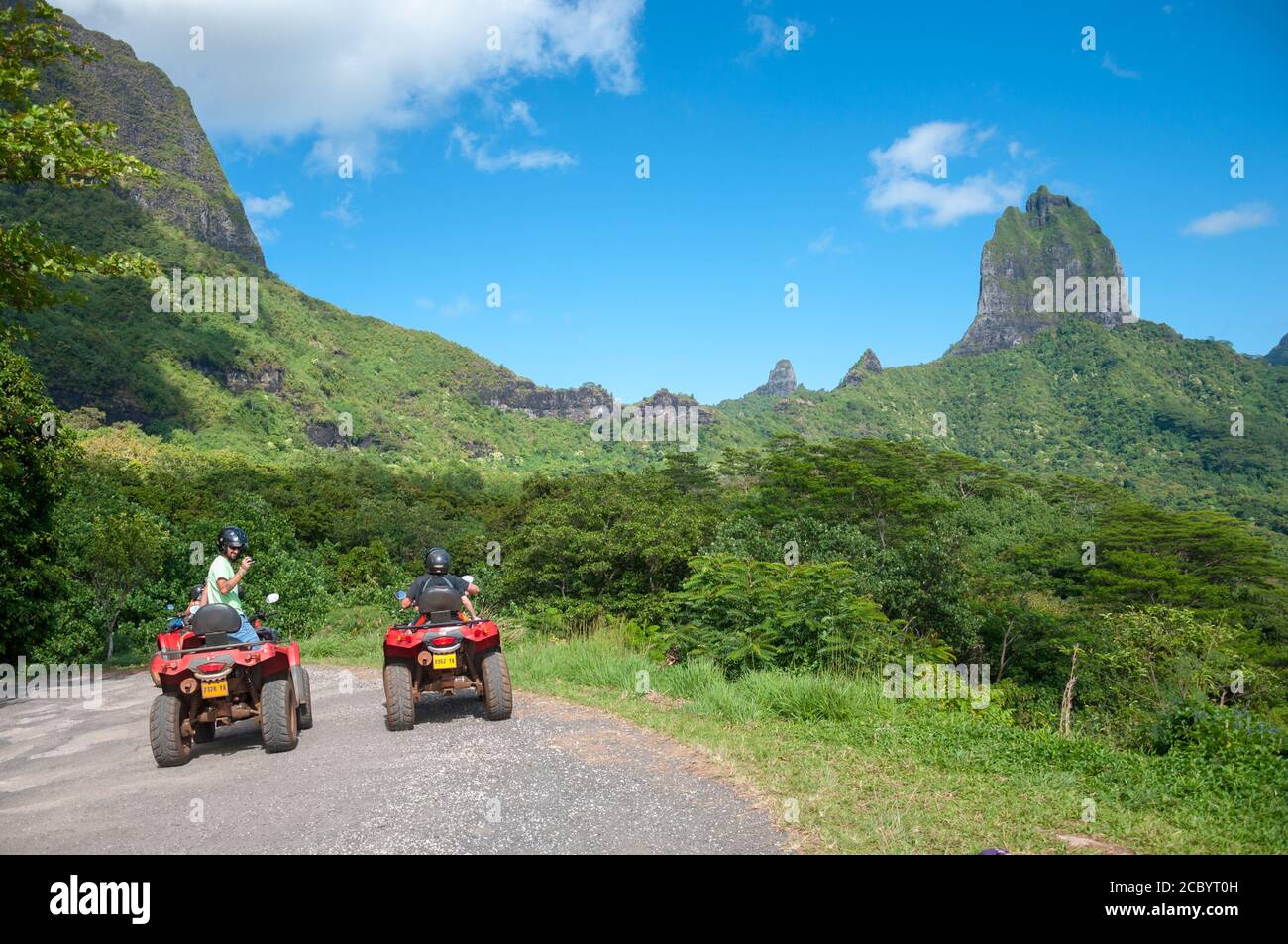 Un petit groupe de jeunes qui portent un casque s'amuser à faire du quad dans une colline près des montagnes rocheuses de Moorea, Polynésie française. Banque D'Images