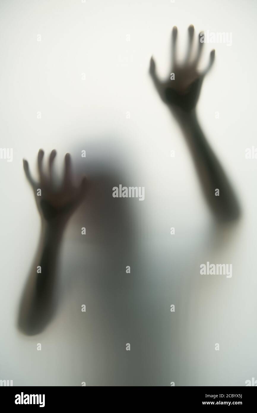 L'ombre sombre des mains et du corps derrière le verre opaque le rend effrayant dans le concept d'Halloween. Banque D'Images