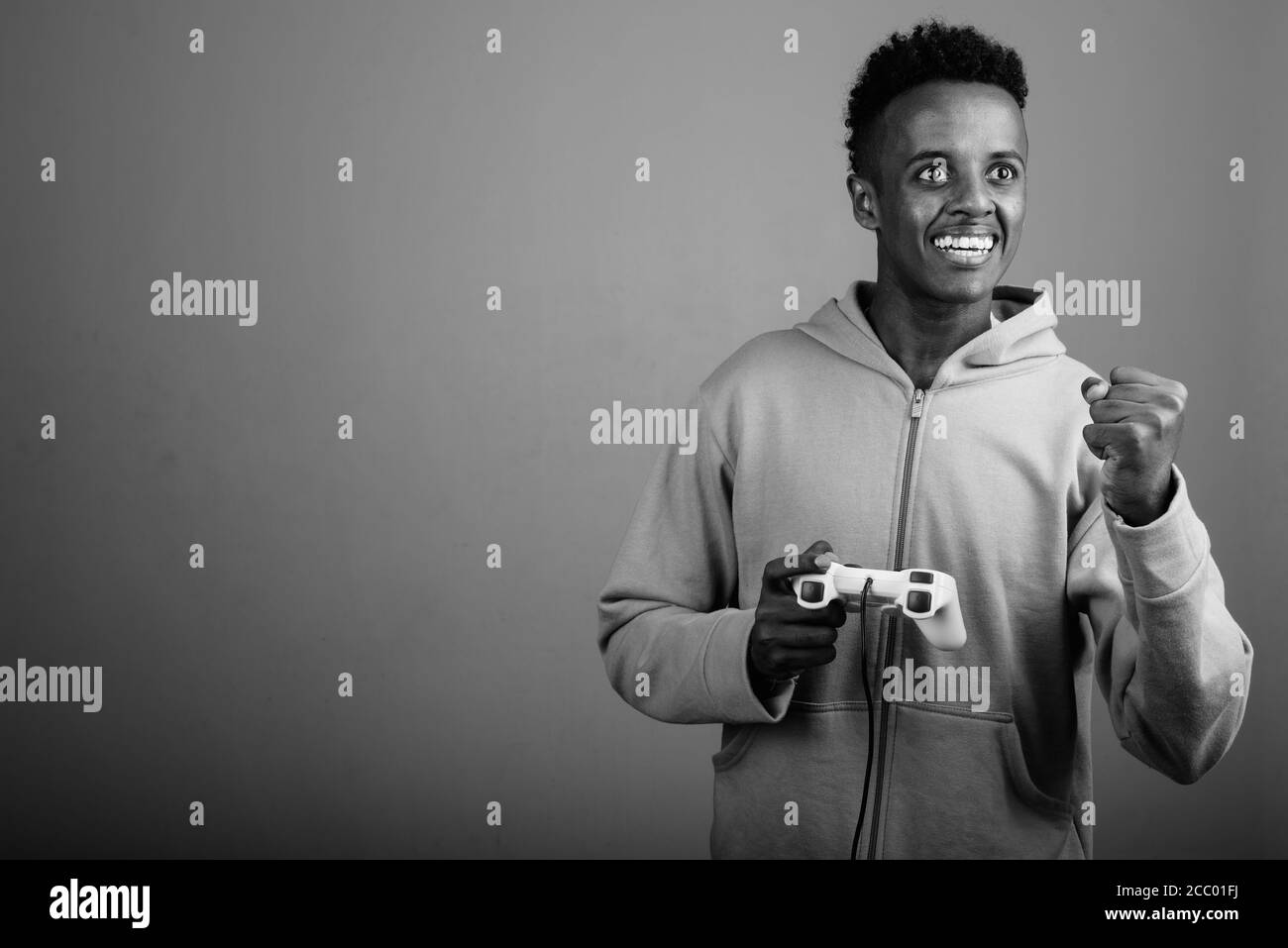 Jeune homme africain charmant jouant à des jeux sur fond gris Banque D'Images Jeune homme africain charmant jouant à des jeux sur fond gris Banque D'Images