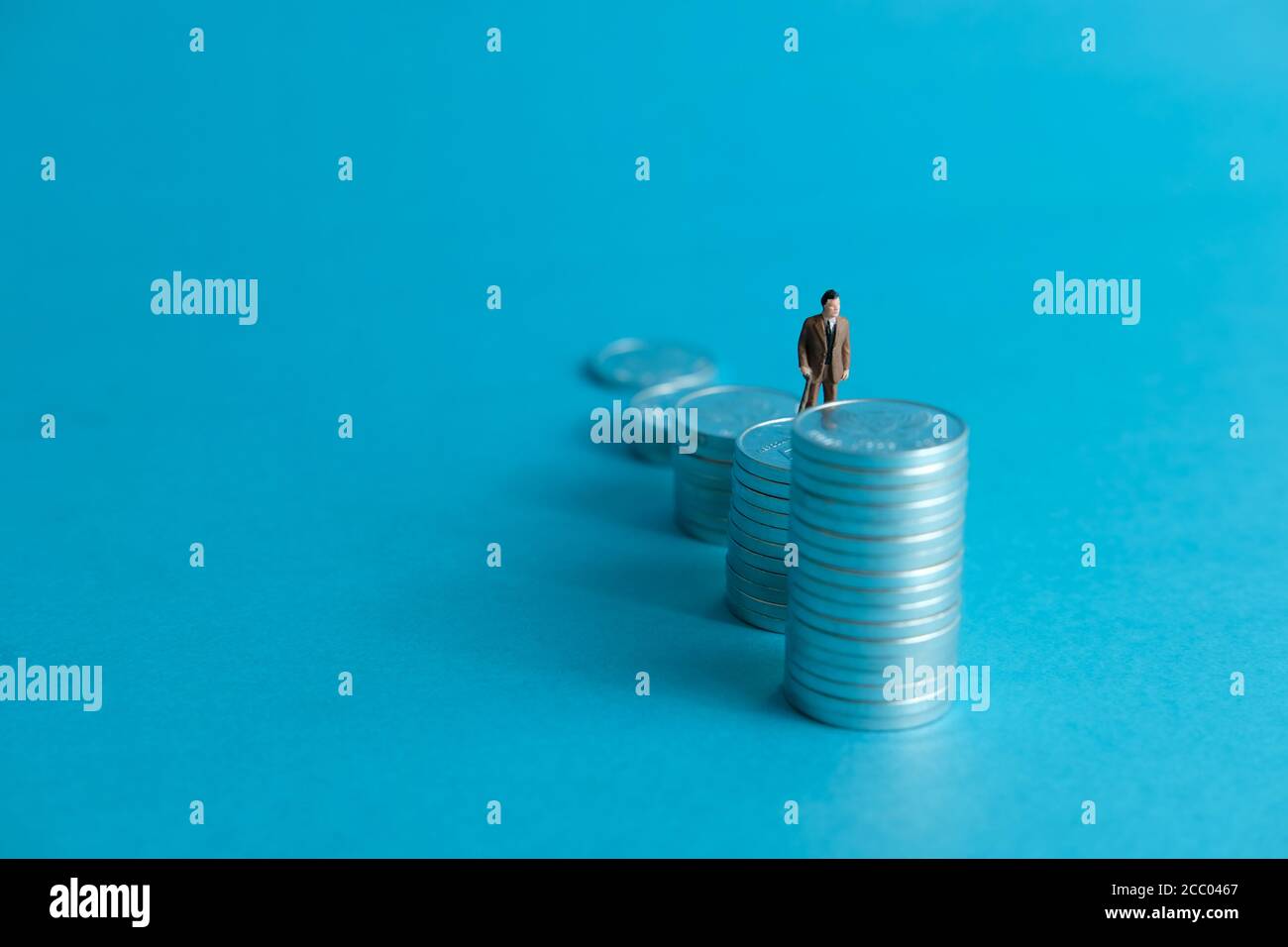 Concept d'affaires miniature - un vieux debout sur la pile de pièces échelle pour faire des investissements financiers Banque D'Images