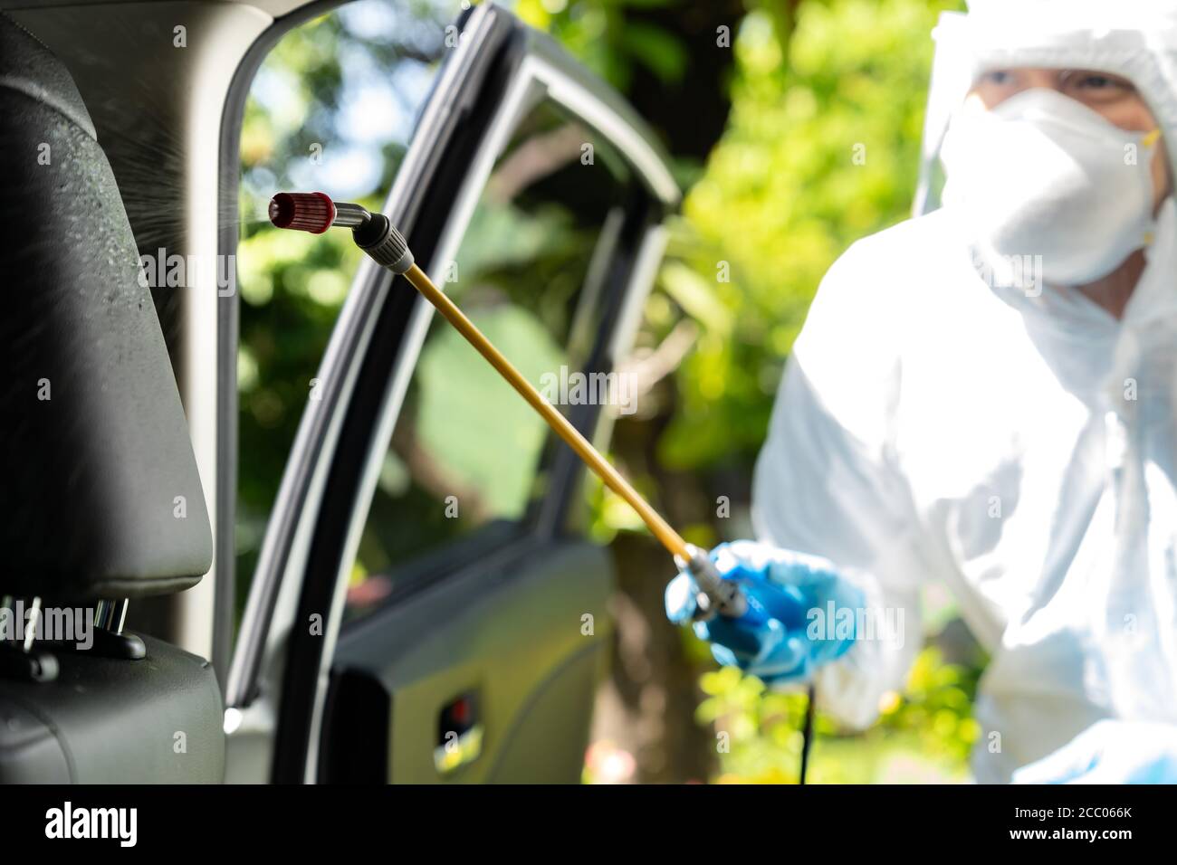 Gros plan du nettoyage en aérosol d'alcool chimique à l'intérieur de la voiture pour désinfecter et décontaminer le coronavirus covid-19 par un nettoyant spécialisé portant un prot personnel Banque D'Images