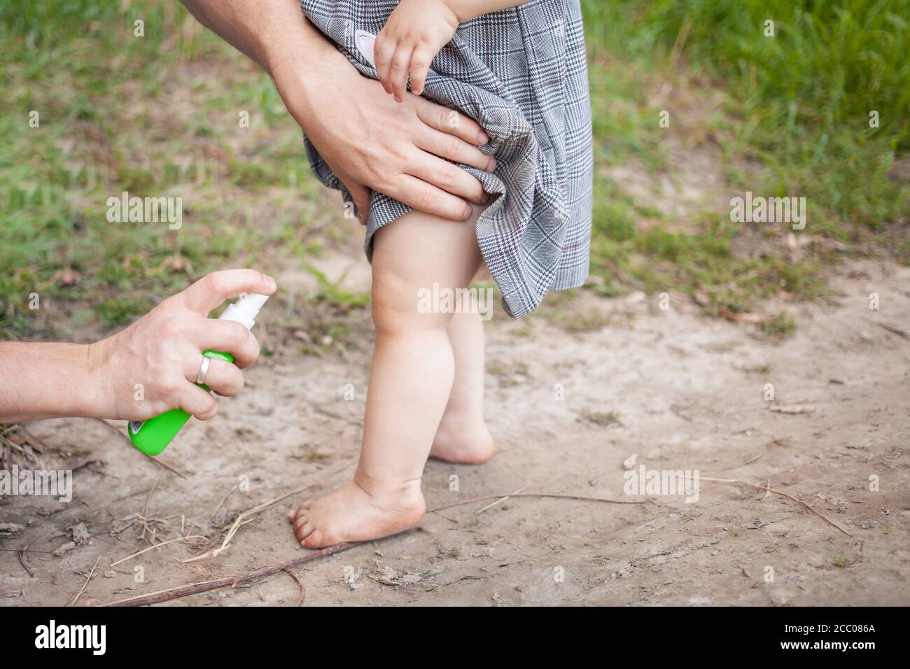 Papa traite sa fille avec un spray moustique. L'homme utilise du spray sur  les bras et les jambes de l'enfant. Protection contre les moustiques dans  la forêt. Vaporiser du mois Photo Stock -