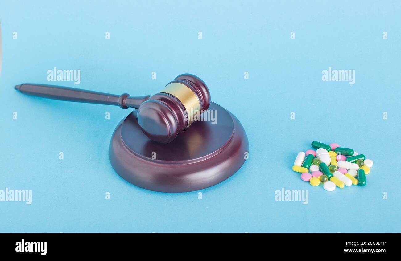 Une pile de pilules et un gavel judiciaire sur fond bleu. Le concept de pilules de qualité inférieure et de médicaments contrefaits en médecine, l'espace de copie pour le texte, un Banque D'Images