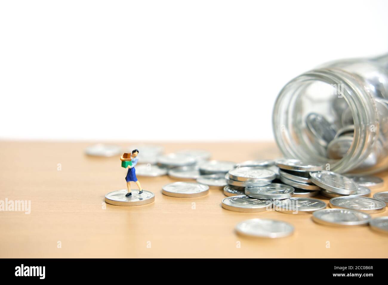 dépenses mensuelles, les femmes dépensent des économies pour faire leurs achats. Les personnes miniatures se font une photographie conceptuelle. Banque D'Images