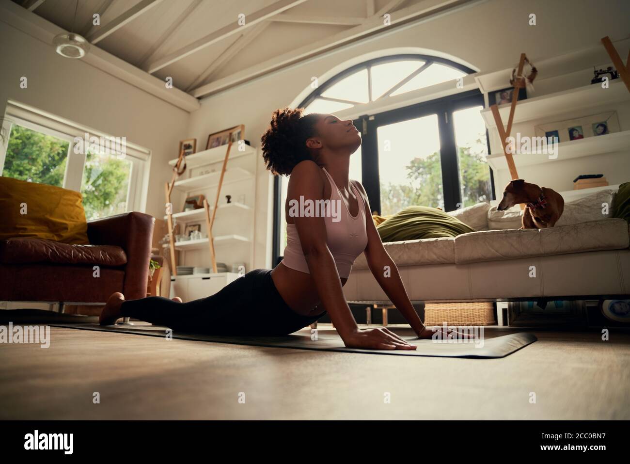 Vue à angle bas de la jeune femme africaine faisant de l'exercice d'étirement sur le tapis de yoga à la maison Banque D'Images