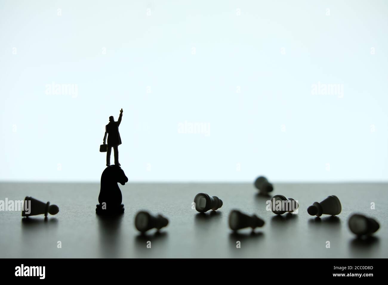 Photo conceptuelle de stratégie d'affaires - Silhouette d'homme d'affaires miniature pointant à l'envers, debout sur un morceau de cheval d'échecs Banque D'Images