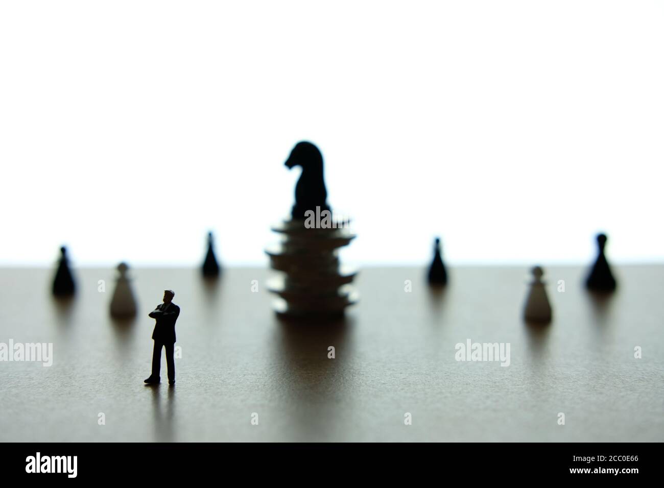 Photo conceptuelle de la stratégie d'affaires - Silhouette homme d'affaires miniature debout pièce d'échecs de cheval devant à la pile de pièces Banque D'Images