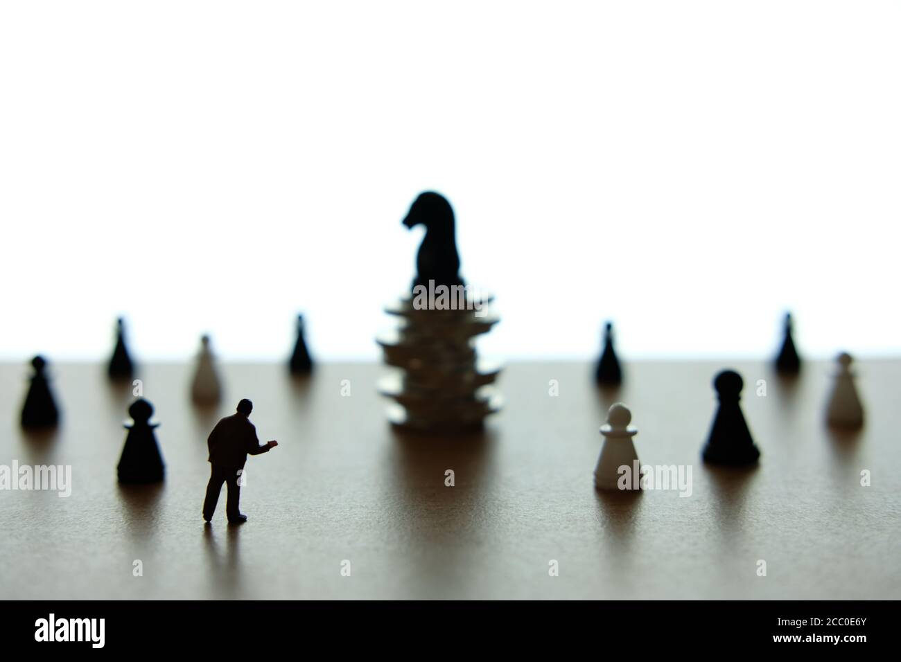 Photo conceptuelle de la stratégie d'affaires - Silhouette homme d'affaires miniature debout pièce d'échecs de cheval devant à la pile de pièces Banque D'Images