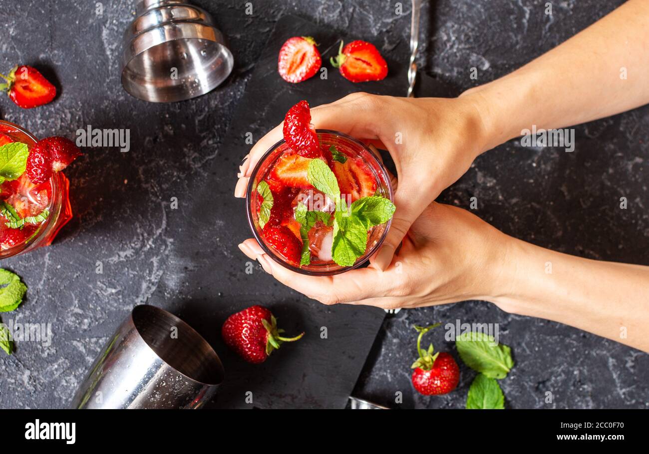 Les mains des femmes ont un verre de mojito de fraise sur fond de pierre noire. Vue de dessus Banque D'Images