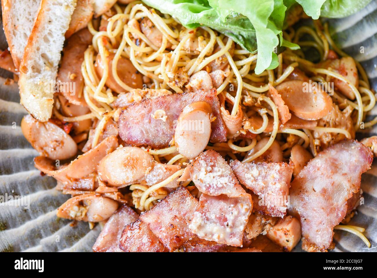 Remuez les spaghetti épicés frits avec des légumes au jambon à la saucisse et du fromage sur l'assiette, vue du dessus Banque D'Images