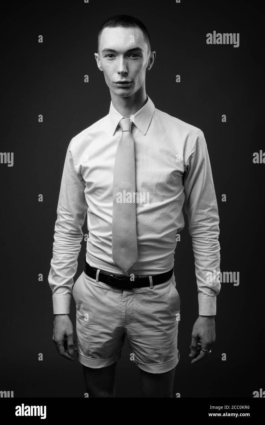 Jeune homme d'affaires androgyne beau sur fond gris Banque D'Images