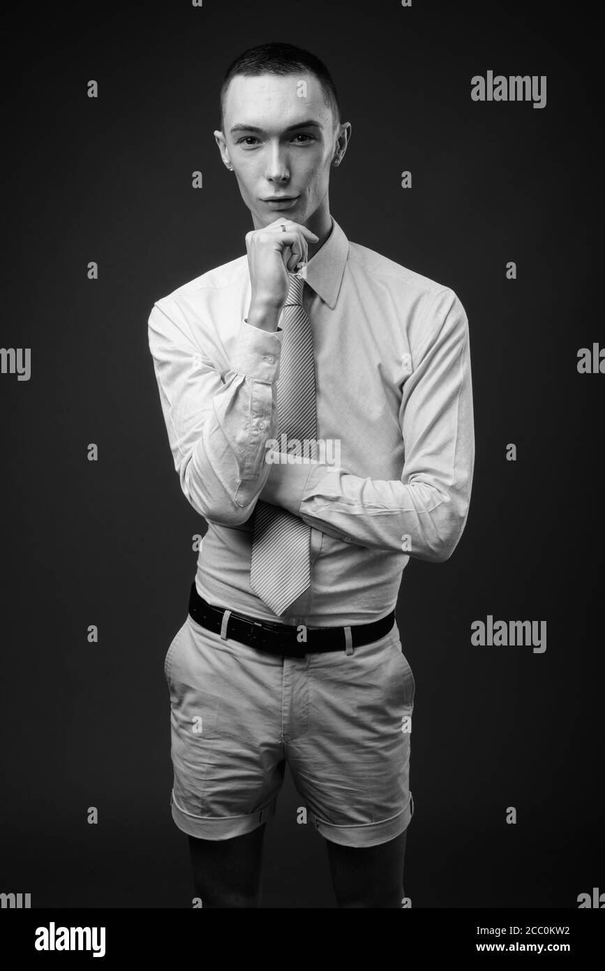 Jeune homme d'affaires androgyne beau sur fond gris Banque D'Images