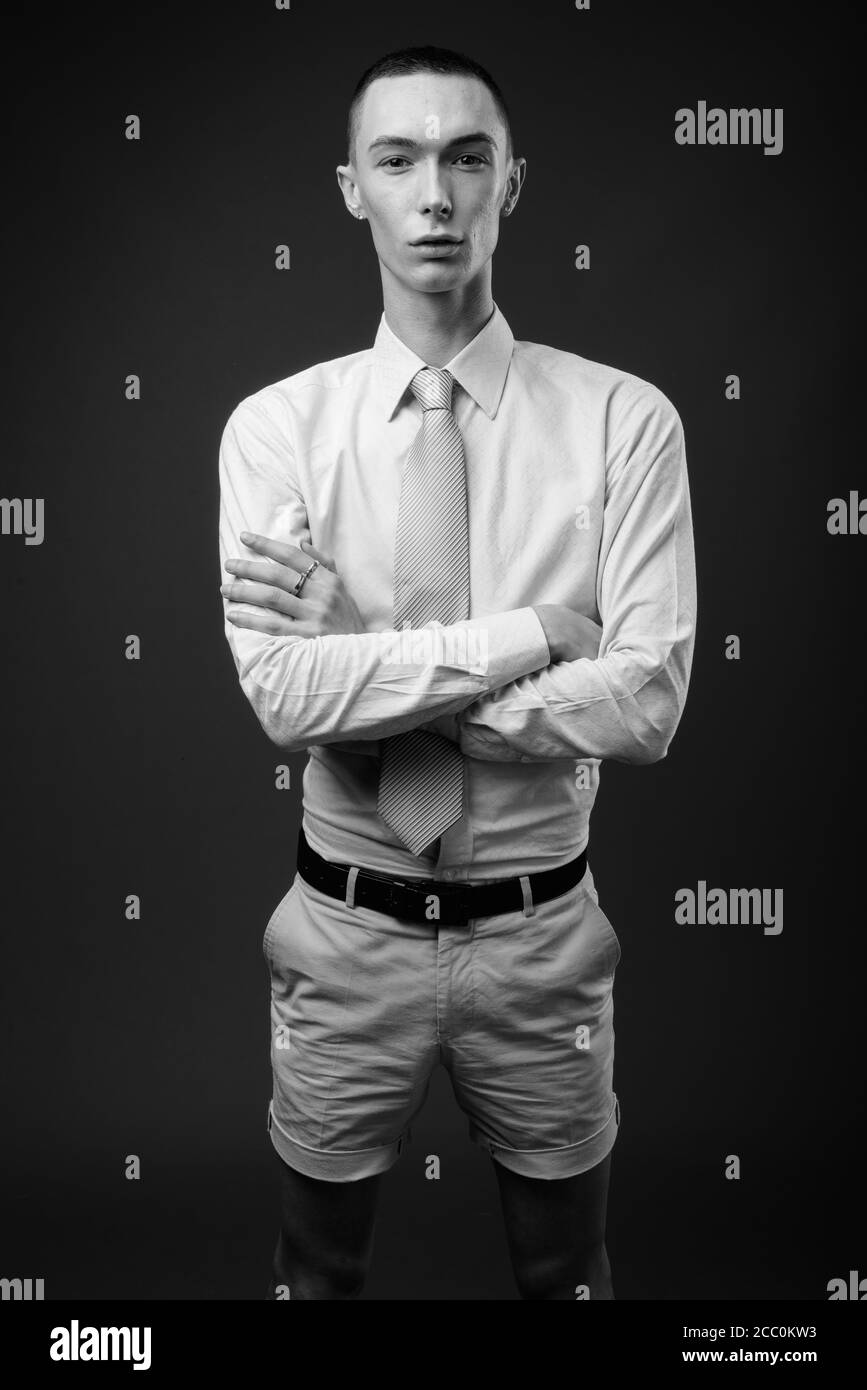 Jeune homme d'affaires androgyne beau sur fond gris Banque D'Images