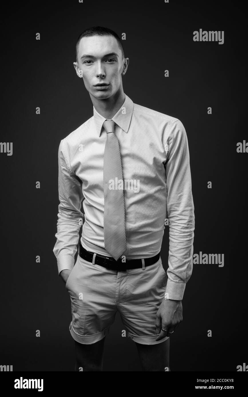 Jeune homme d'affaires androgyne beau sur fond gris Banque D'Images