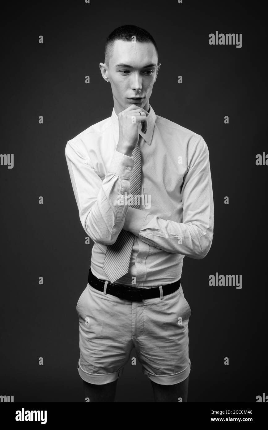 Jeune homme d'affaires androgyne beau sur fond gris Banque D'Images