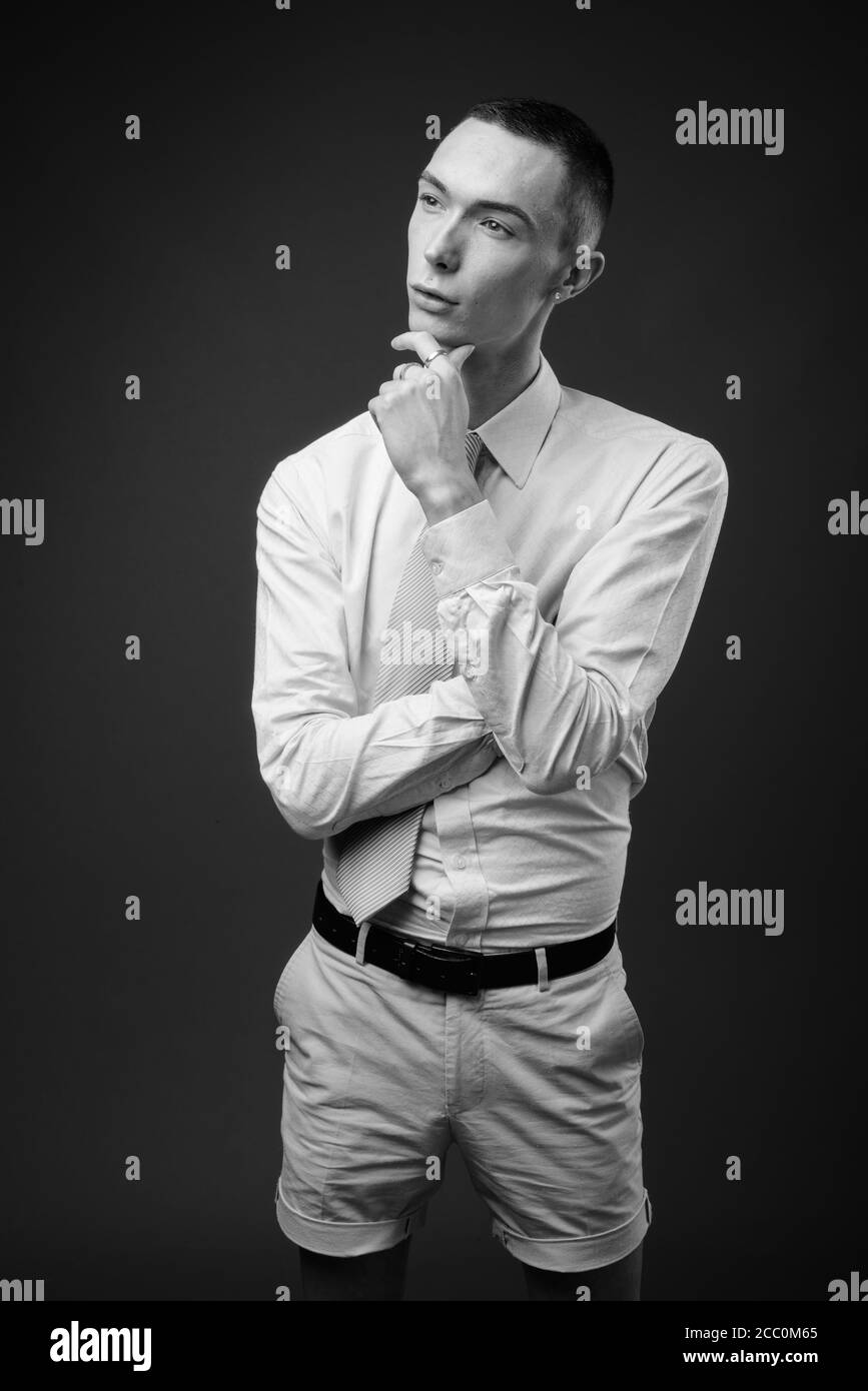 Jeune homme d'affaires androgyne beau sur fond gris Banque D'Images