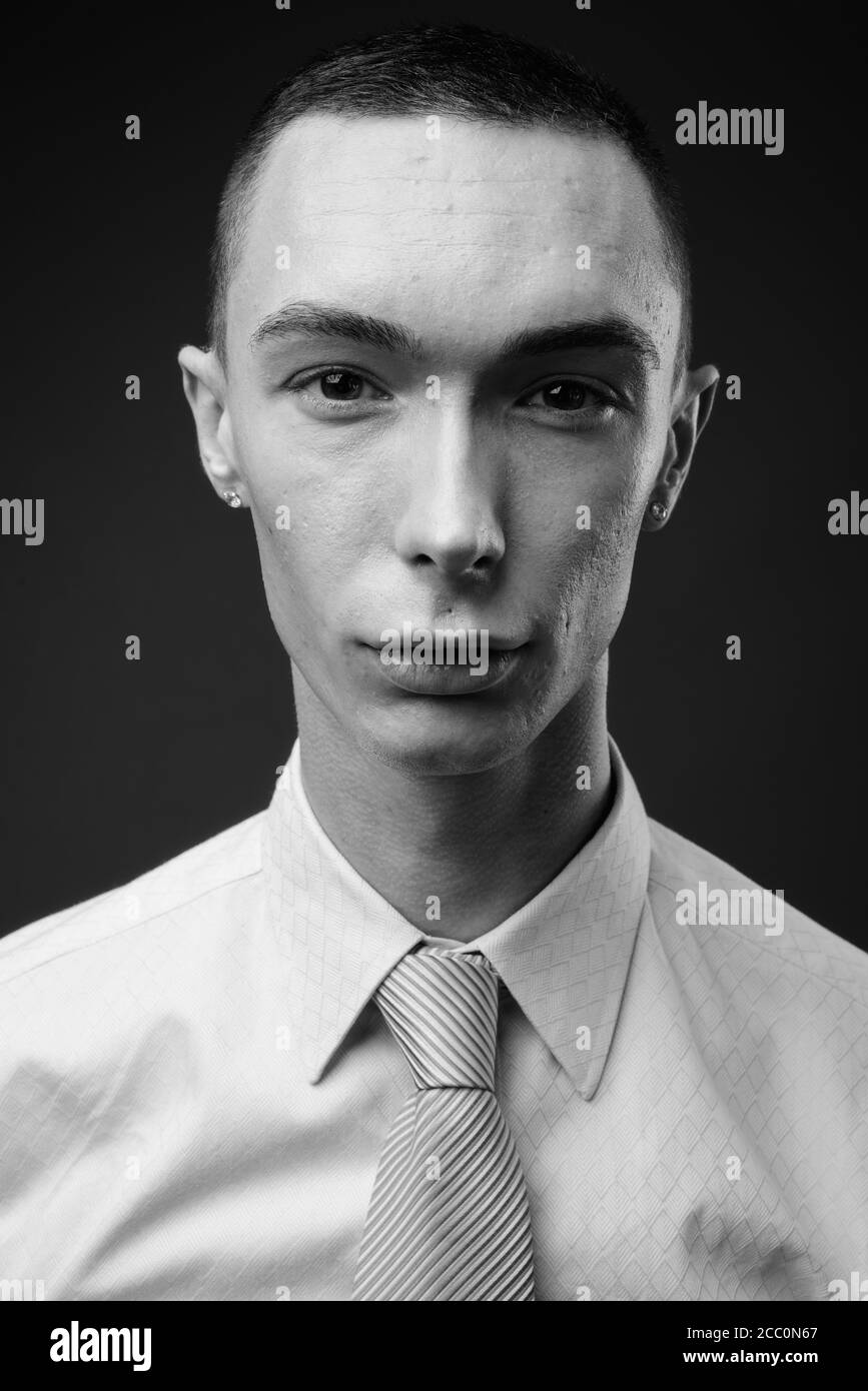 Jeune homme d'affaires androgyne beau sur fond gris Banque D'Images