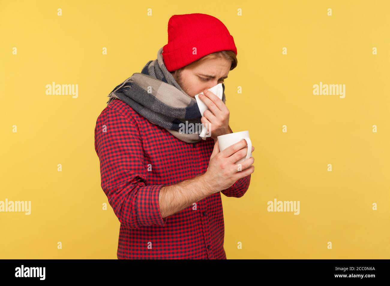 Grippe-malade qui traite le nez qui coule, qui souffle dans la serviette, qui tient le thé chaud de tasse, qui se sent mal avec l'éternuement toux fièvre, mal de gorge, souffrant de grippe saisonnière inf Banque D'Images