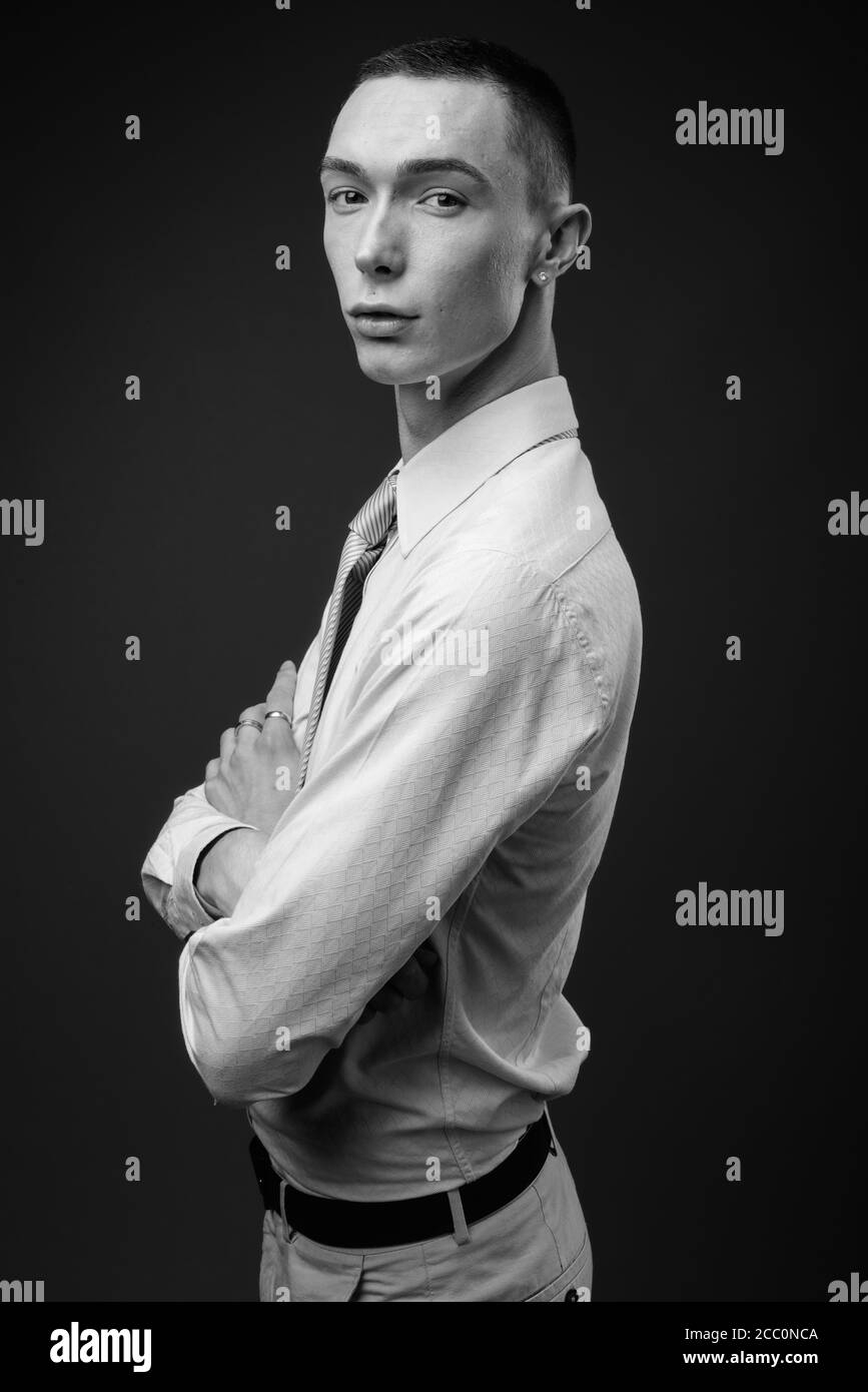 Jeune homme d'affaires androgyne beau sur fond gris Banque D'Images