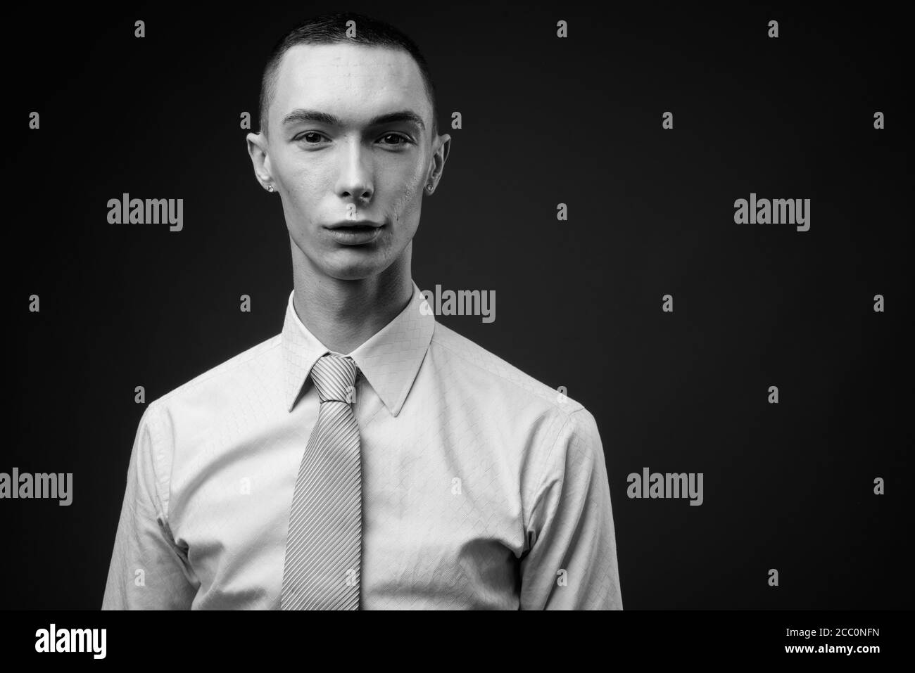 Jeune homme d'affaires androgyne beau sur fond gris Banque D'Images