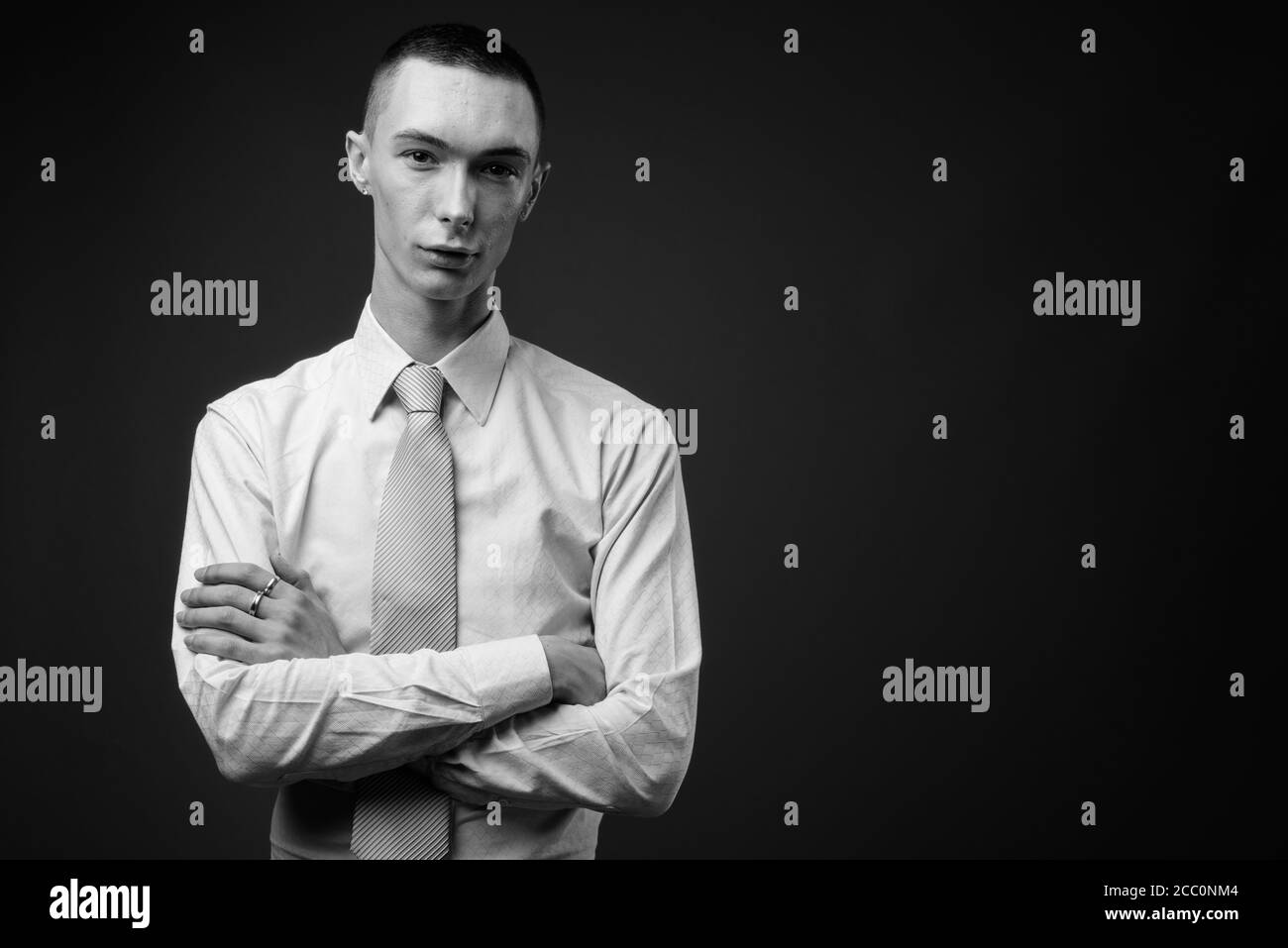 Jeune homme d'affaires androgyne beau sur fond gris Banque D'Images