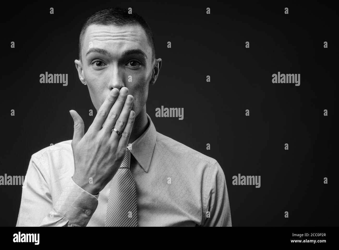 Jeune homme d'affaires androgyne beau sur fond gris Banque D'Images