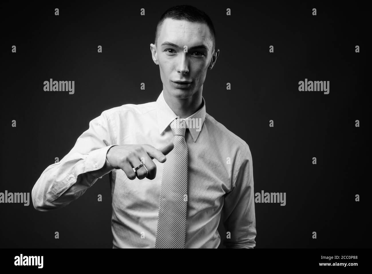 Jeune homme d'affaires androgyne beau sur fond gris Banque D'Images