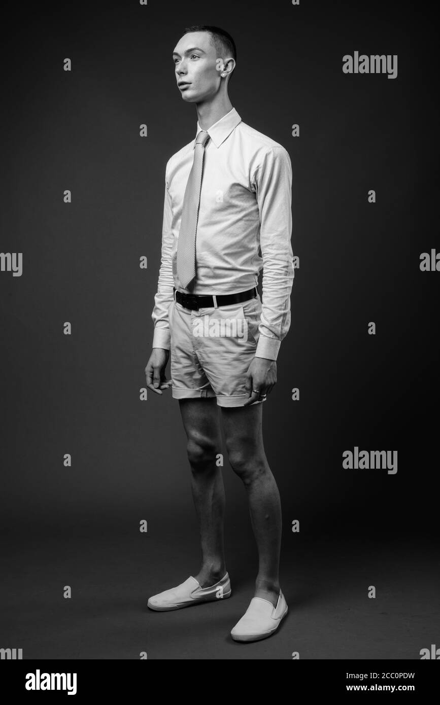 Jeune homme d'affaires androgyne beau sur fond gris Banque D'Images