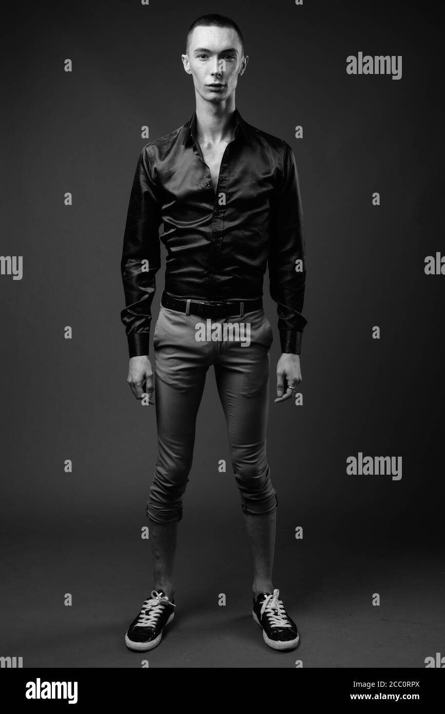 Jeune homme d'affaires androgyne beau sur fond gris Banque D'Images