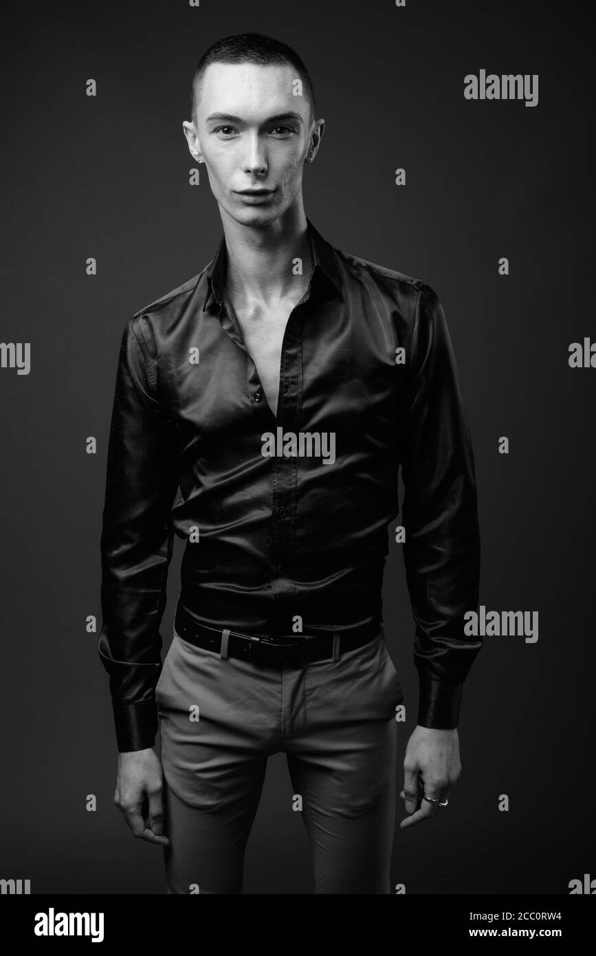 Jeune homme d'affaires androgyne beau sur fond gris Banque D'Images