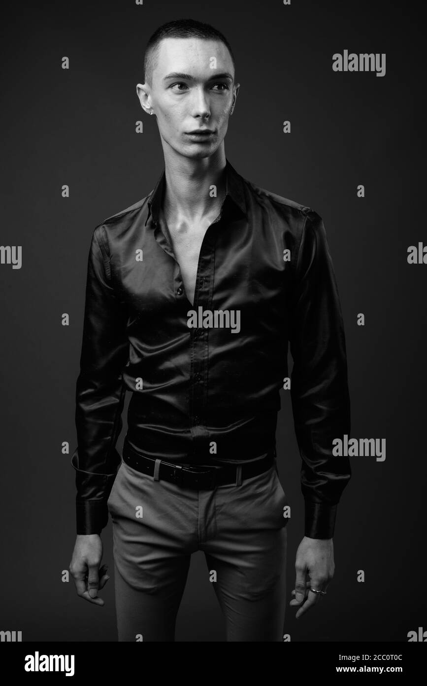 Jeune homme d'affaires androgyne beau sur fond gris Banque D'Images