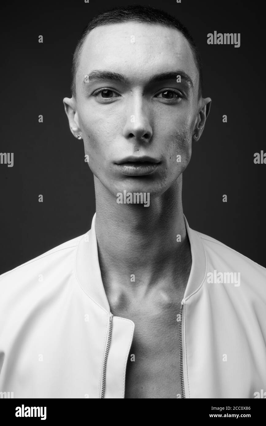 Jeune homme androgyne beau sur fond gris Banque D'Images
