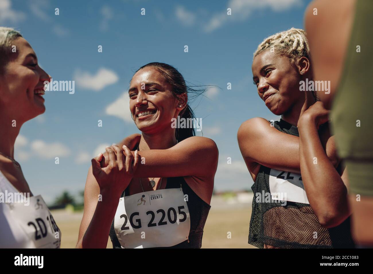 Groupe d'athlètes féminins qui étirent les bras sur une piste de course. Les femmes qui font des exercices d'échauffement au stade. Banque D'Images