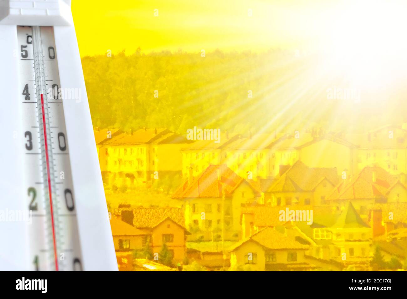 Vague de chaleur - concept de réchauffement de la planète. Chaleur estivale dans la ville. Un thermomètre à 42 ° C sur fond d'une ville brumeuse. Arrière-plan jaune. Banque D'Images