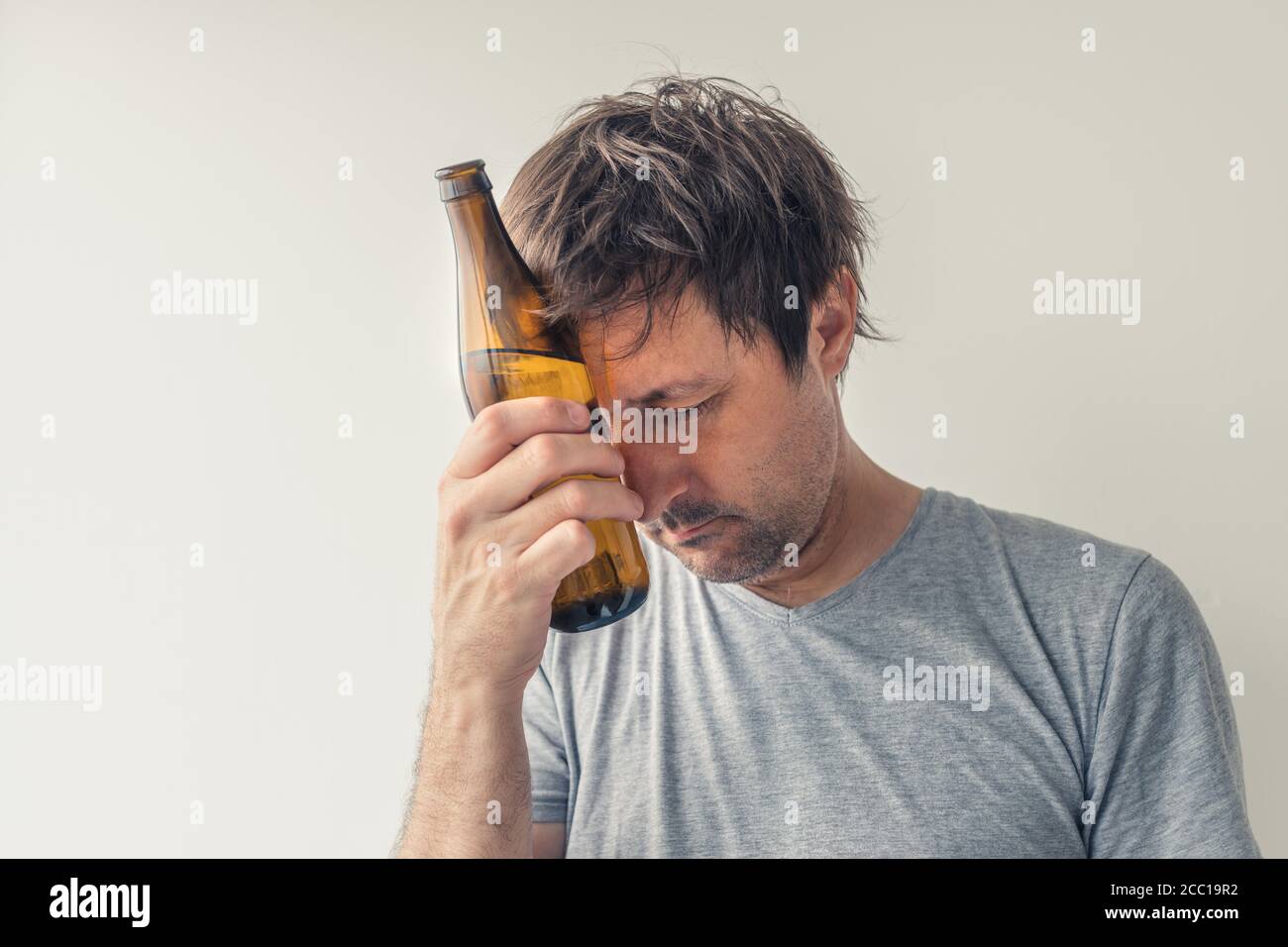 Alcoolisme et gueule de bois concept, homme avec bouteille de bière Banque D'Images