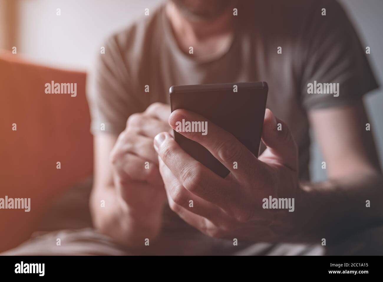 Homme utilisant le téléphone mobile à la maison, gros plan sur les mains des hommes accro au smartphone, mise au point sélective Banque D'Images