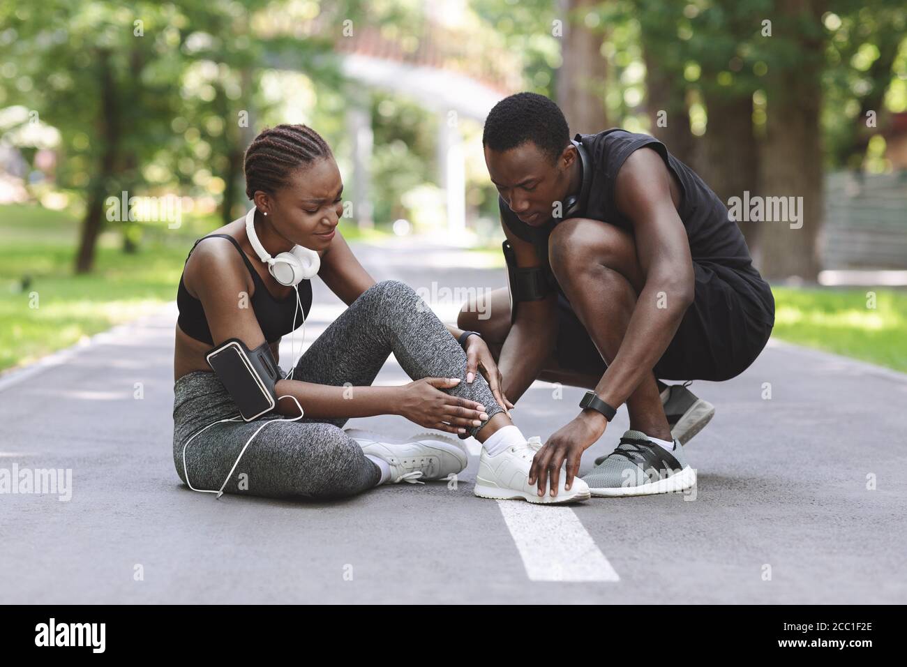 Blessures par jogging. Black Guy aidant petite amie souffrant de la cheville tentaculaire après la course Banque D'Images