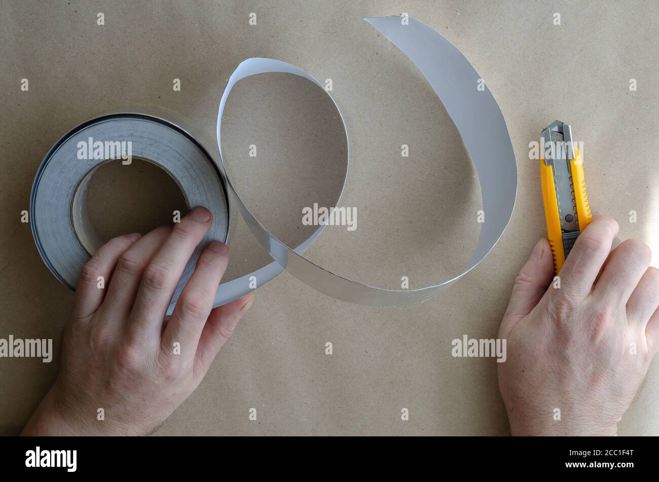 Les mains d'un homme caucasien d'âge moyen travaillent avec du ruban adhésif et un couteau. Services d'isolation thermique et d'humidité. Matériaux isolants modernes. Sélection Banque D'Images