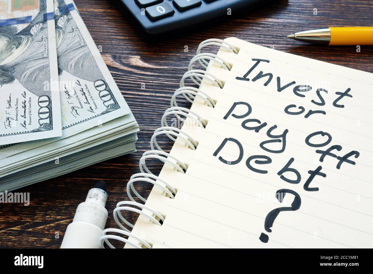 Investissez ou payez la question de la dette dans le bloc-notes. Banque D'Images