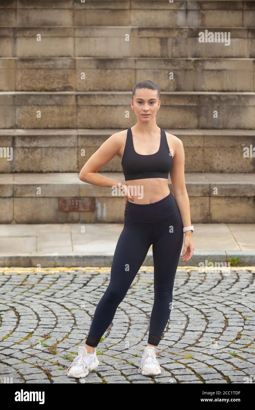 Une jeune femme sportive portant des vêtements de sport debout devant un ensemble de marches, prête pour l'exercice. Banque D'Images