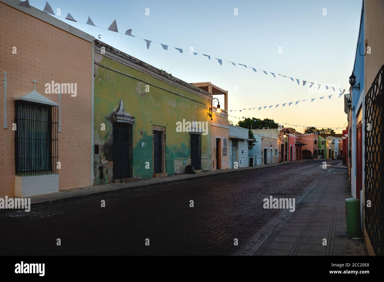 Rue traditionnelle du dôme mexicain avec bâtiments coloniaux colorés et drapeaux après le coucher du soleil, Merida, Yucatan, Mexique Banque D'Images